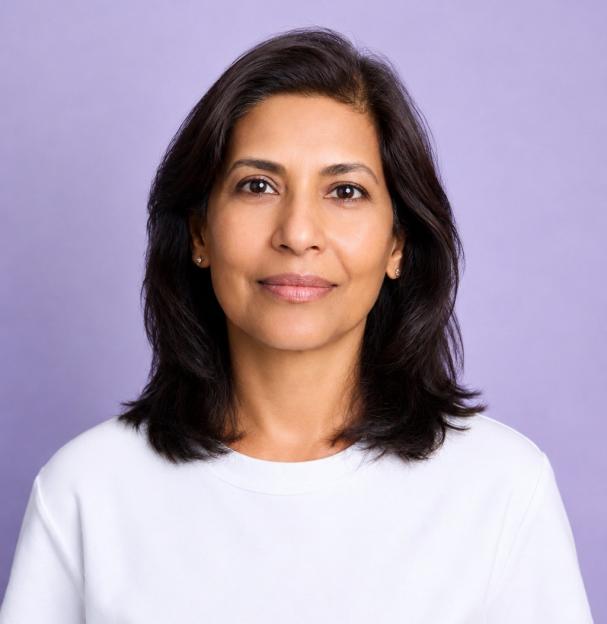 A woman with clear skin, dark hair, and brown eyes looks directly at the camera.