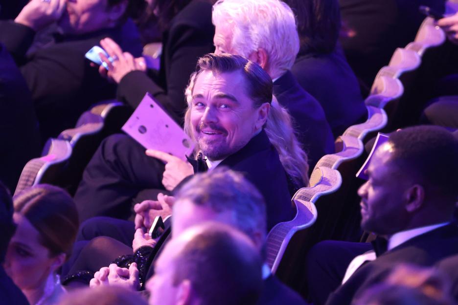 Leonardo DiCaprio smiling while seated in an auditorium.