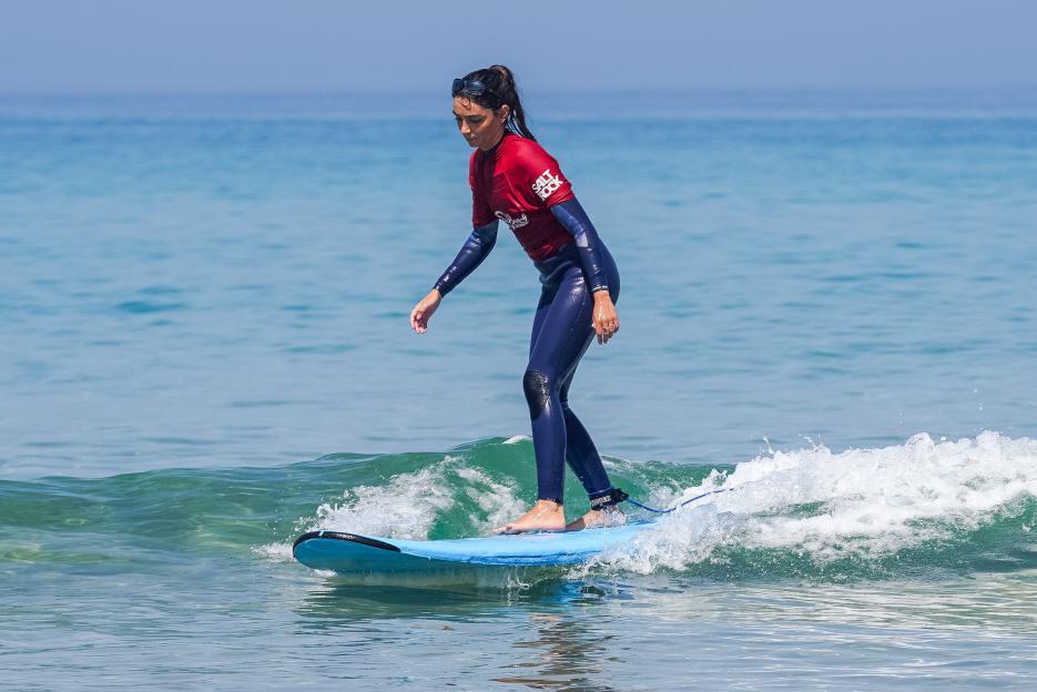 A surfer on a blue board riding a small wave.