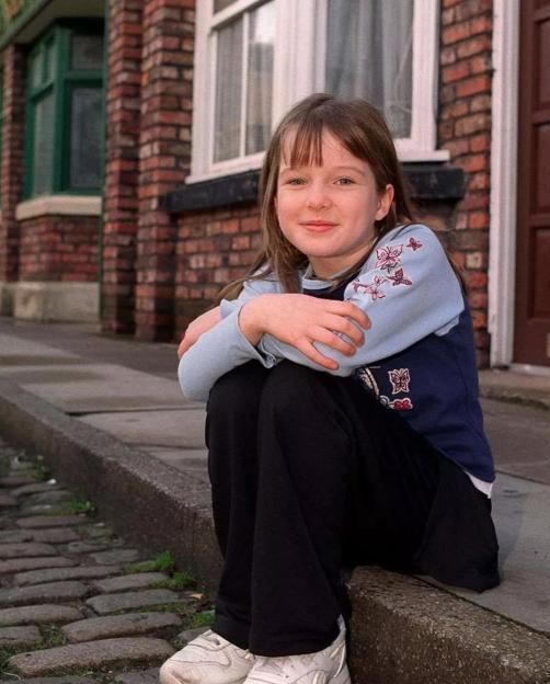 Helen Flanagan as a young girl sitting on a curb.