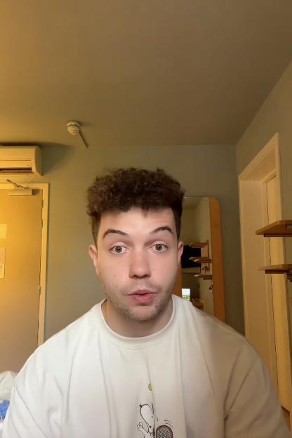 Alex, a male actor, looks directly at the camera with a surprised expression.