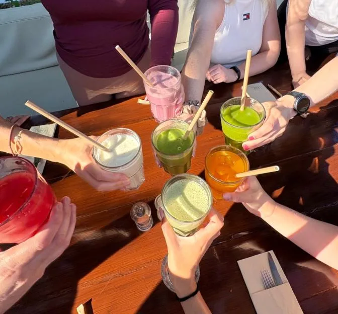 A group of people making a toast with various colorful smoothies.