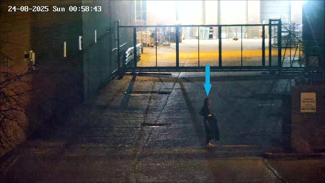 CCTV image of Sheryl Wilkins with a blue arrow pointing to her, near a car park.