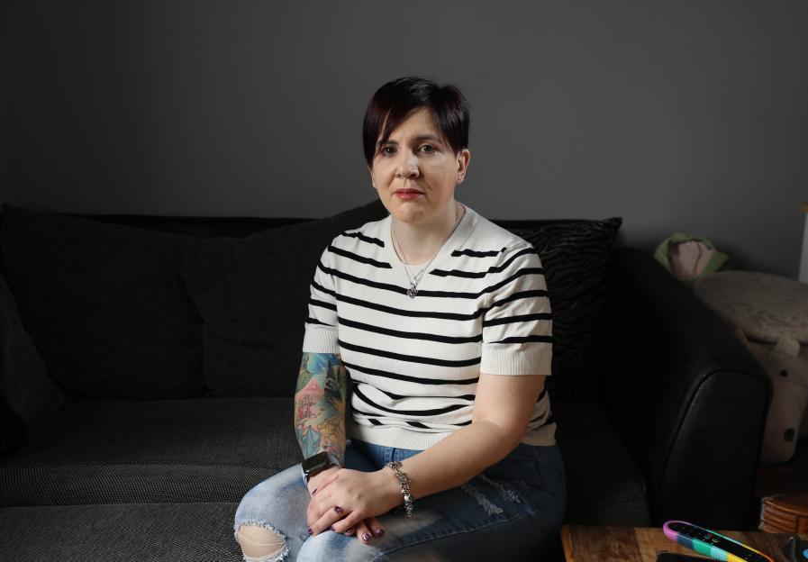 Tammy Downing sits on a couch in her home.