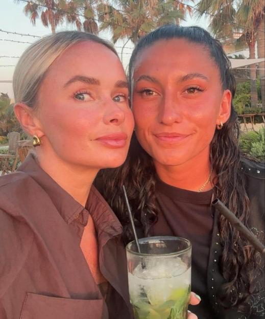 MAFS star Leah and her new girlfriend posing together, with a drink in the foreground.