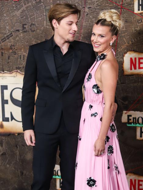 Millie Bobby Brown in a pink dress and Jake Bongiovi in a black suit.