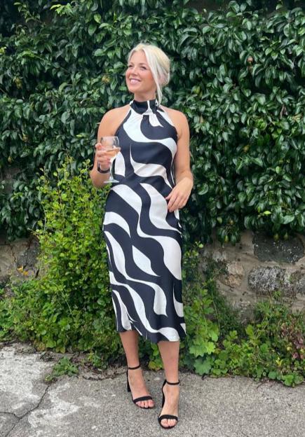 Pamela Pritchard in a black and white patterned dress, holding a glass of wine.