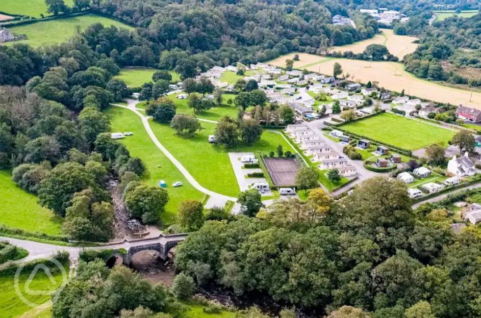 Aerial view of Harford Bridge Park with its mature parkland, tents, tourers, shepherd's hut, pods, tennis court, and river.