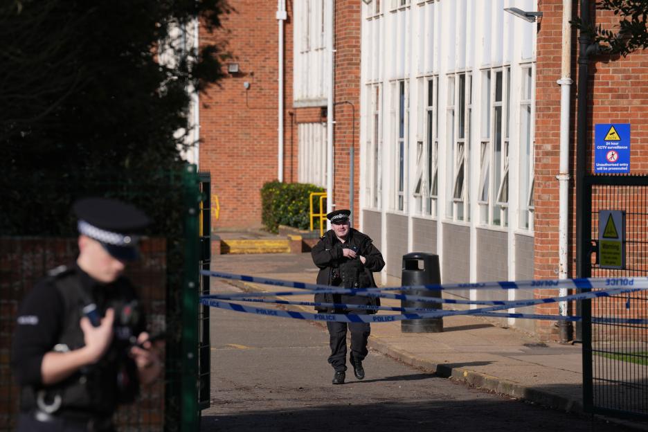 Police tape cordons off the entrance to Thorpe St Andrew School, with two police officers visible.