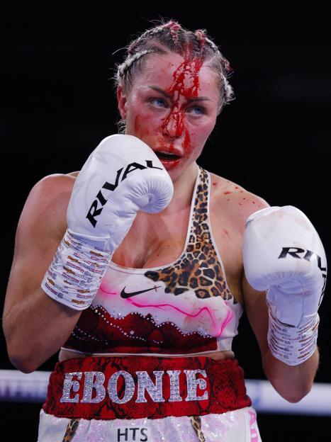 Ebonie Cotton in action during her fight against Molly McCann with blood visible on her face and shoulder.