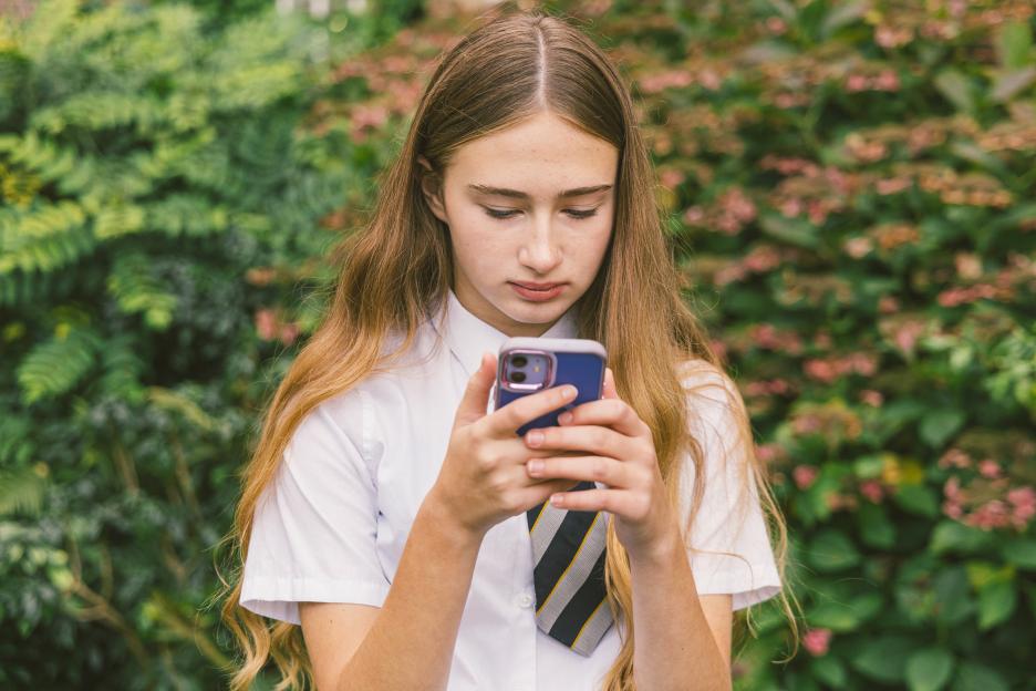 Teenage Girl in School Uniform Using Smartphone Outdoors