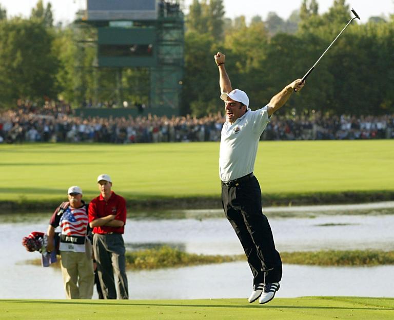 Paul McGinley (R) of Ireland leaps in the air afte