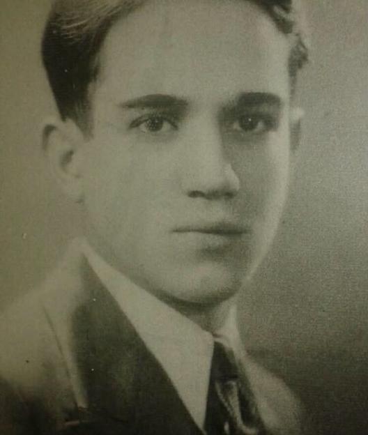 A young man with light hair and dark eyes wearing a suit and tie.