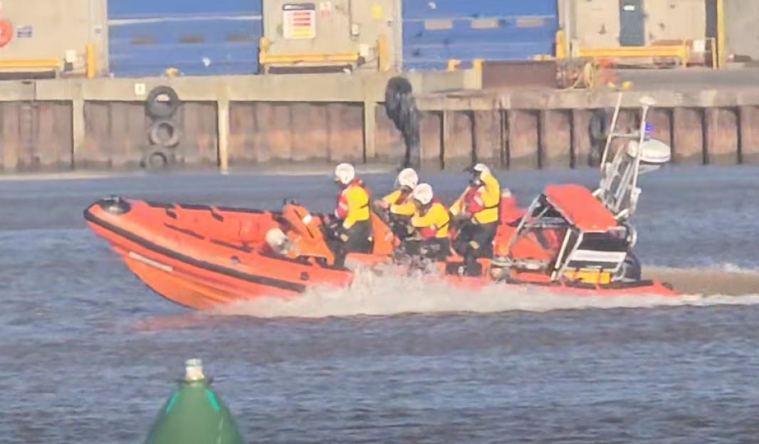 Rescue boat with four crew members on a body of water.