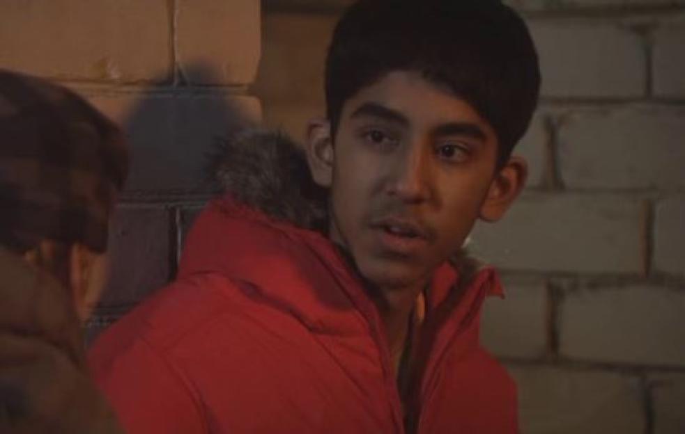 Dev Patel as Anwar Kharral in a red puffer jacket.