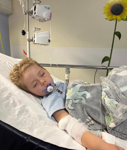 Edison, 4, asleep in a hospital bed with an IV drip and a bandaged arm after nearly dying from diabetic ketoacidosis.