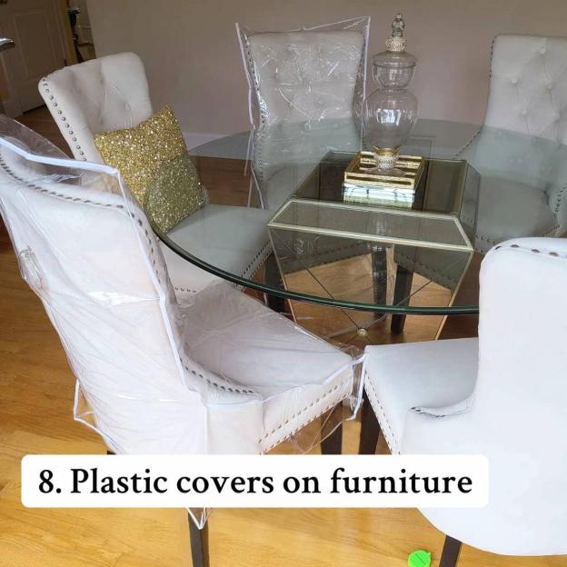 Dining room with chairs covered in clear plastic.