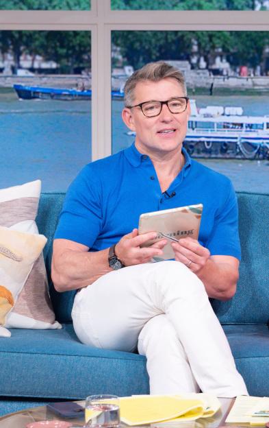 a man and a woman sit on a couch with a tablet that says bbc on it