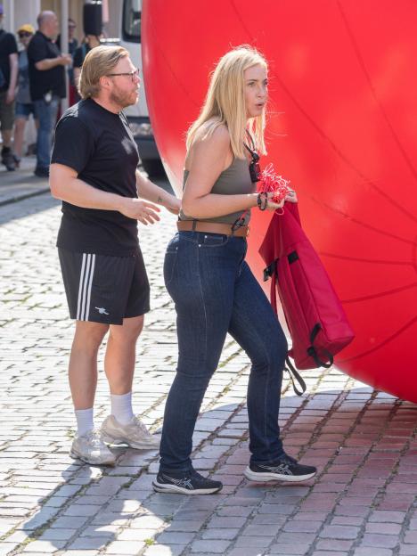 Josie Gibson and Rob Beckett moving a giant red ball for a TV show.