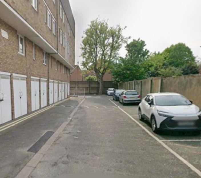 Cadbury Way, Bermondsey with a row of garages and parked cars.