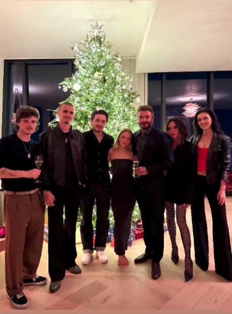 David and Victoria Beckham with their kids in front of a Christmas tree.