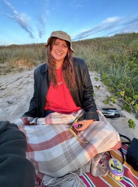 Photo of Daisy Catterall sitting on a sand dune.