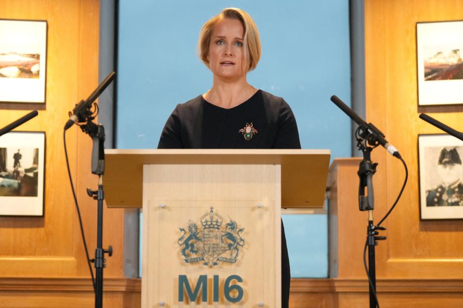 Blaise Metreweli, new head of Britain's MI6, speaking at a podium with the MI6 logo.
