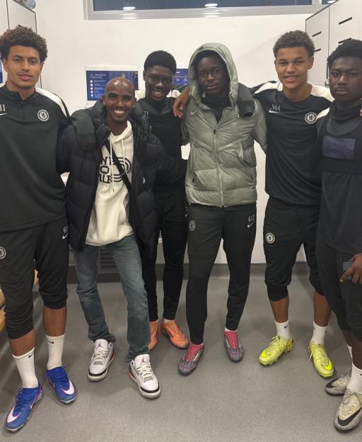Six young men and one adult man pose for a photo in what appears to be a locker room.