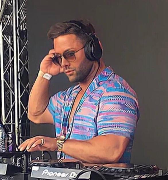 Man in a colorful shirt and sunglasses wearing headphones while DJing.