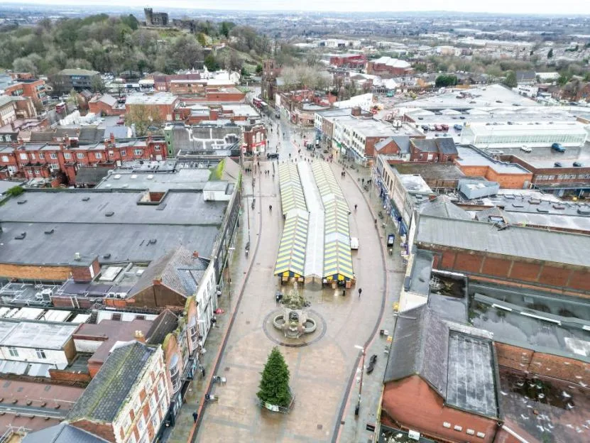 An aerial view of the town center of Dudley, showing empty market stalls and surrounding buildings under an overcast sky.