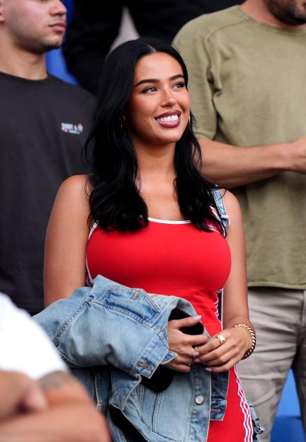 A woman in a red Adidas tank top and blue denim jacket attending the Andorra v England World Cup Qualifier.