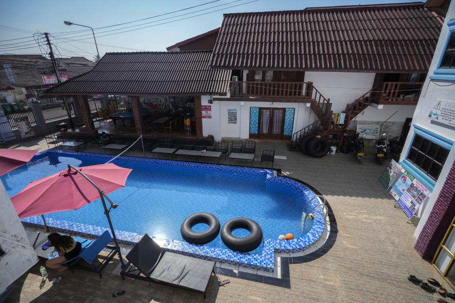 A tourist resting near a swimming pool at Nana Backpackers hostel in Vang Vieng, Laos.