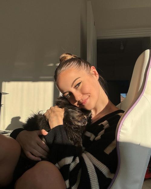 Holly H smiling and holding a small black dog.