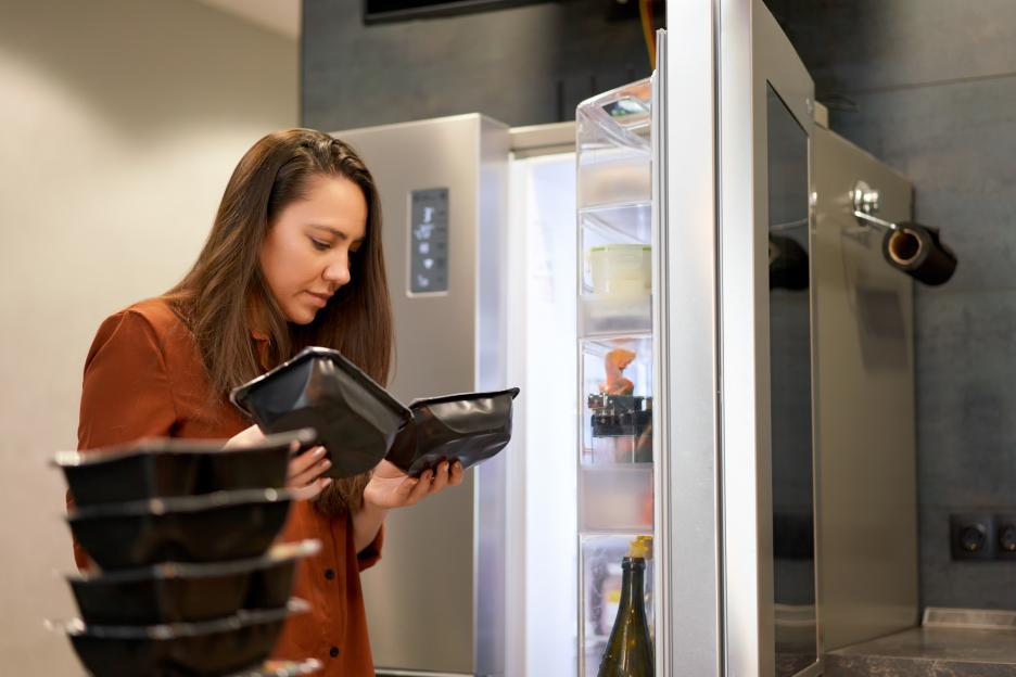 Woman reading the expiry date on a plastic food container.