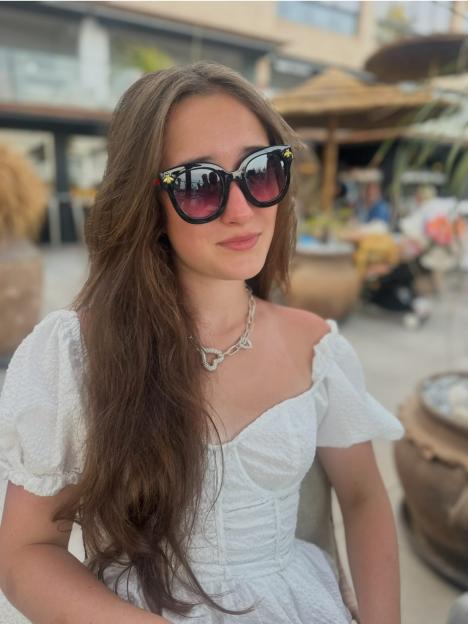 Denise Van Outen's daughter Betsy in a white dress and black sunglasses.