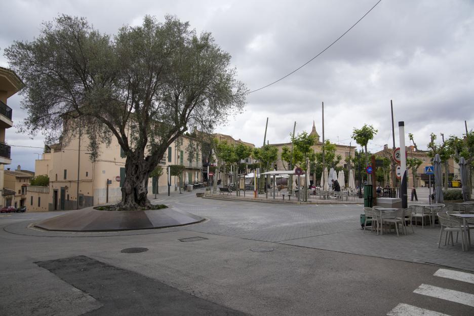 The Village Square in Santa Margalida, Majorca, with outdoor seating areas and buildings under a cloudy sky.