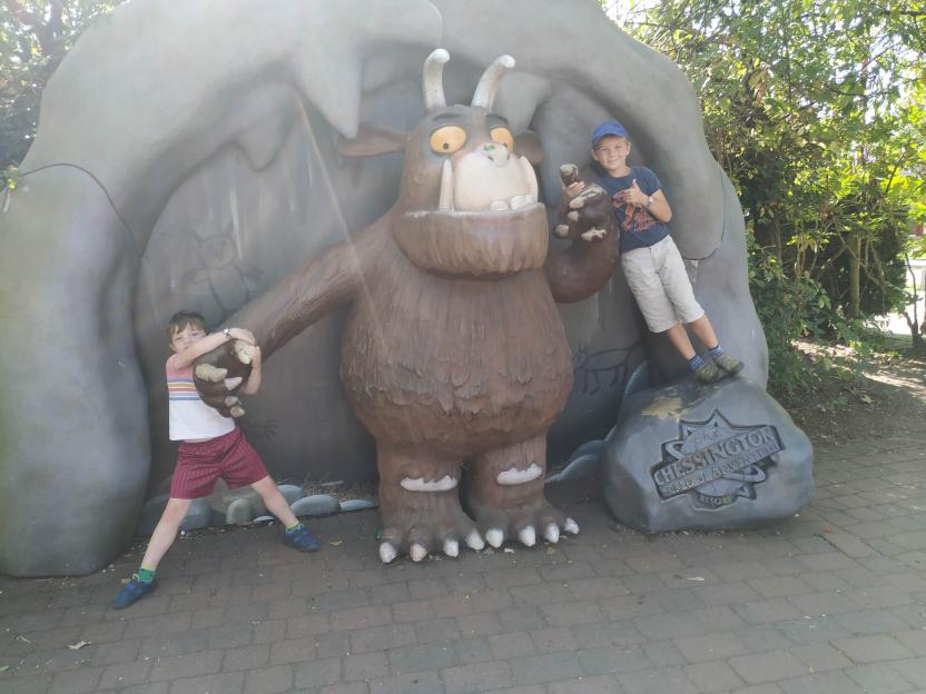 Two boys posing next to a Gruffalo statue with a Chelsington World of Adventures Resort sign.