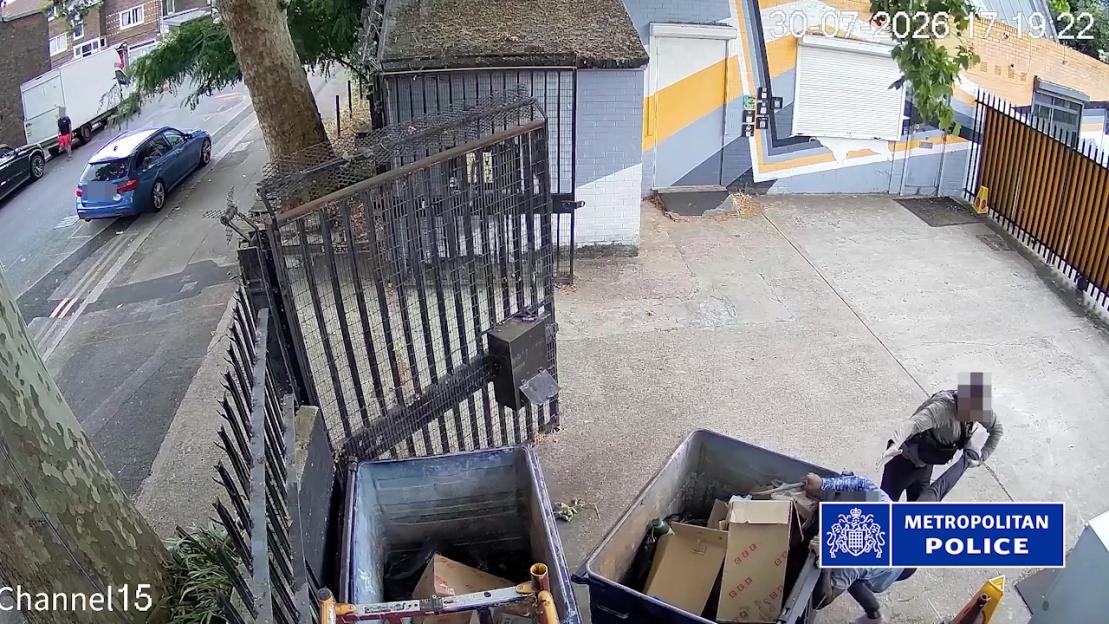 Two police officers restraining a person trying to escape into a bin.