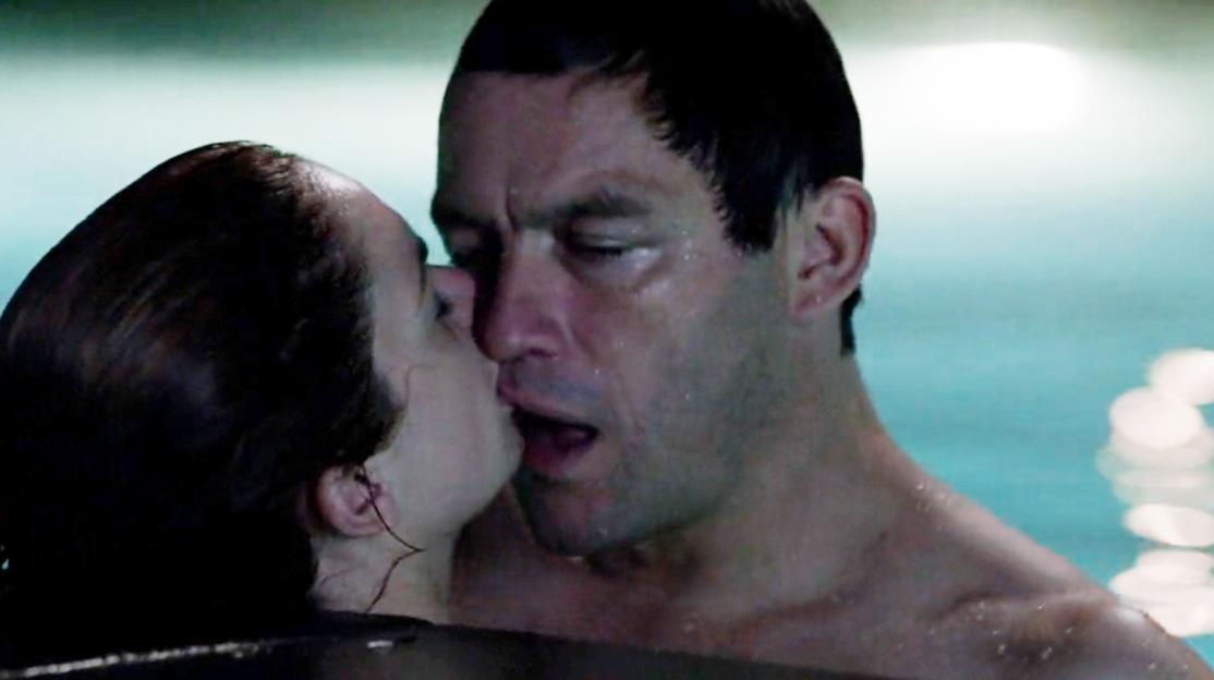 A man and woman kissing passionately in a pool, their faces wet.