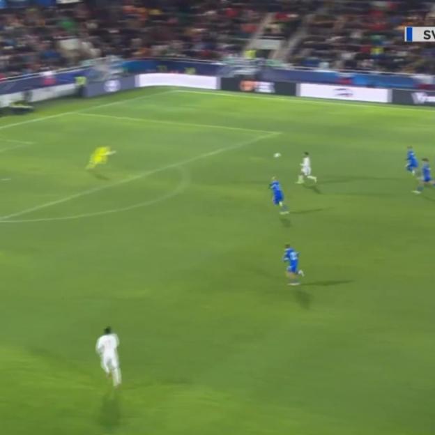 A soccer game in progress with players in white and blue uniforms on a green field.