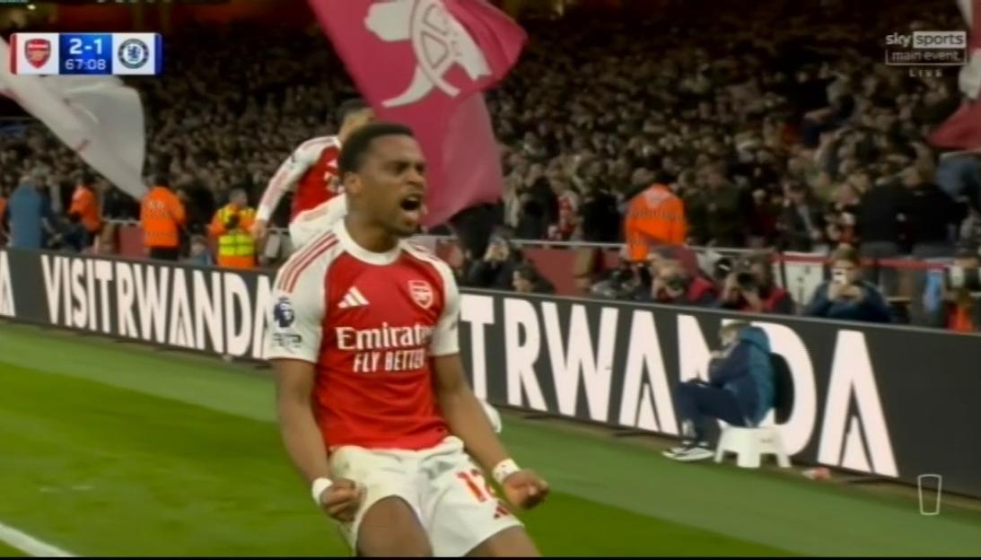 A soccer player in a red and white jersey clenching his fists and yelling in celebration.