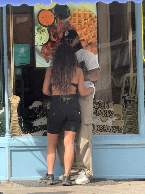 Jesy Nelson and Ben Davies embracing in front of a pancake house window.
