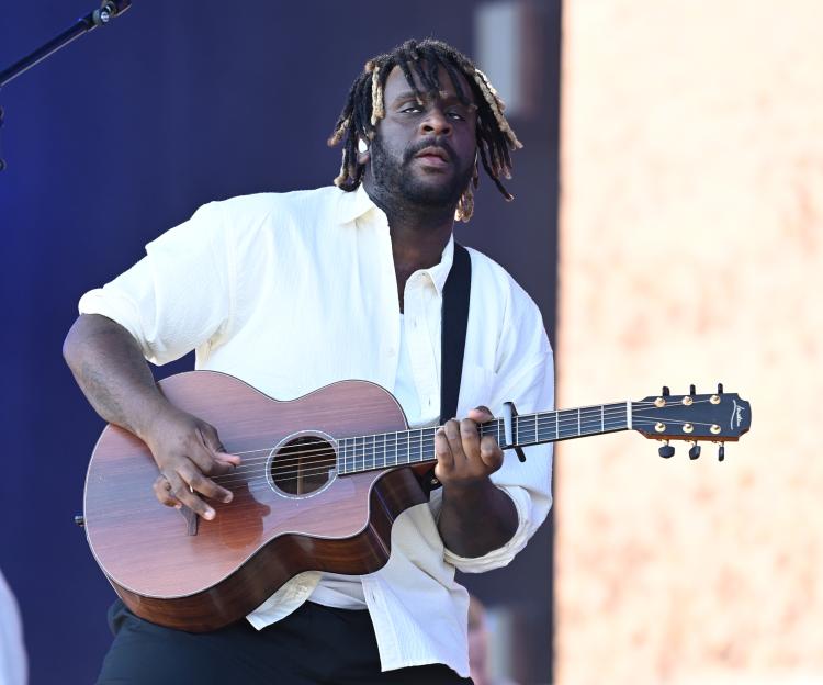 Myles Smith performs on stage while playing an acoustic guitar.