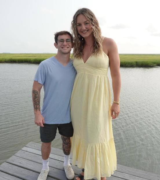 NCAA Champion Lucas Byrd and volleyball star Ellie Holzman standing on a dock over water with marshland in the background.