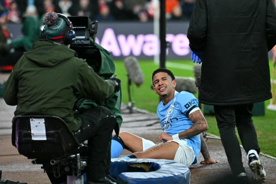 Manchester City's Savinho sits on the ground waiting for treatment during a match.