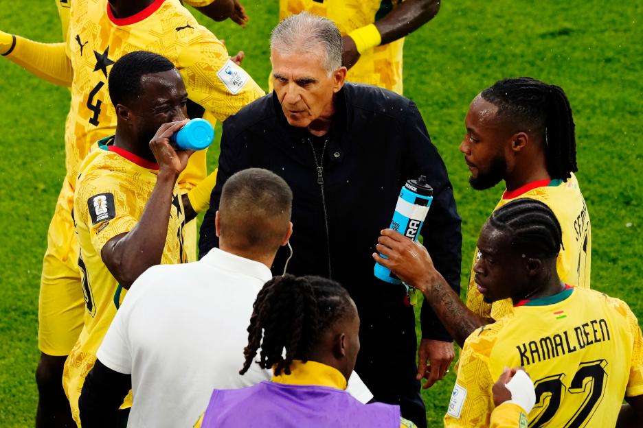 Ghana manager Carlos Queiroz speaks with his players during a hydration break.