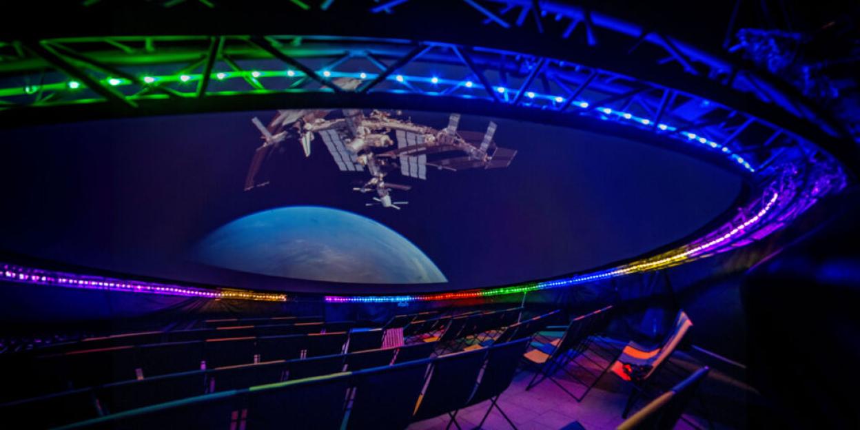 An empty planetarium shows a projection of the International Space Station and Earth.