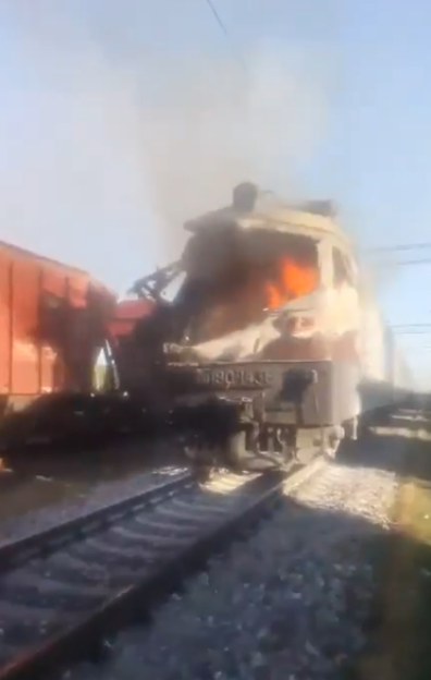 A train locomotive engulfed in flames and smoke.
