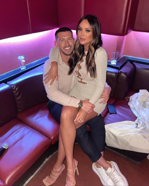 Charlotte Crosby sitting on Jake Ankers' lap on a red couch.