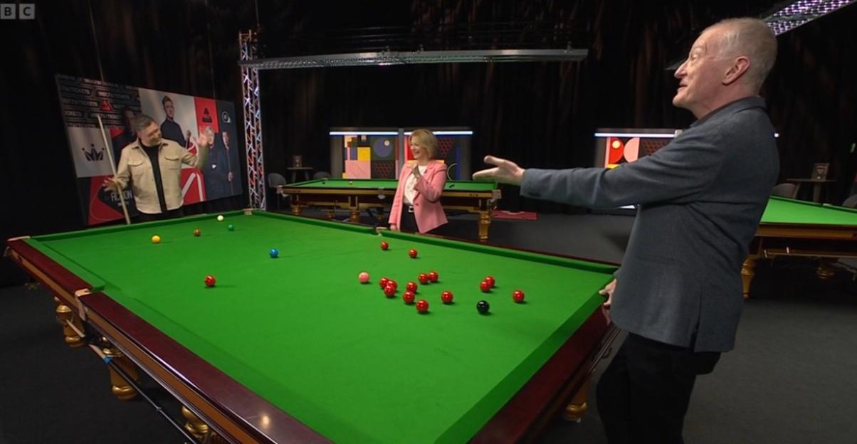 Three commentators reacting to a snooker game, two men and one woman.